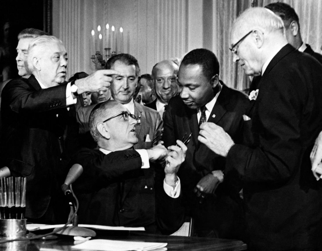 President Lyndon Johnson gives a pen to the Reverend Martin Luther King (second from right) after signing the Civil Rights Act in 1964 in the East Room of the White House.