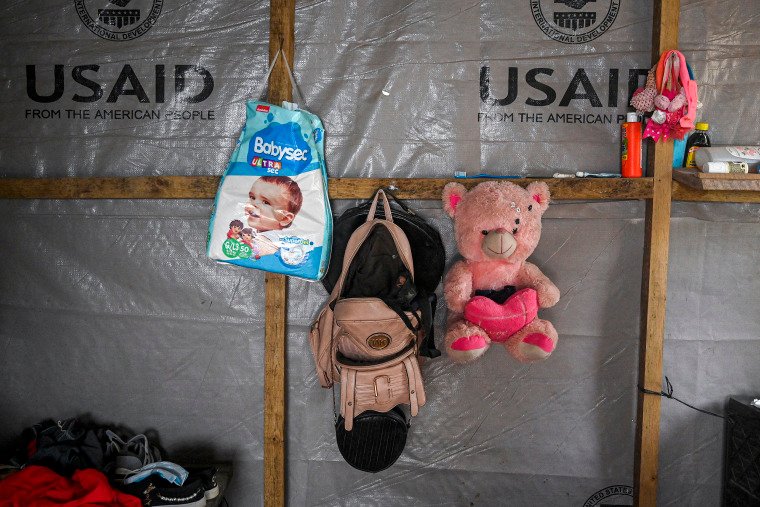 A wall that has a purse, diapers and a teddy beer.