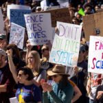 protesters in a crowd with signs reading Science Saves Lives, Don