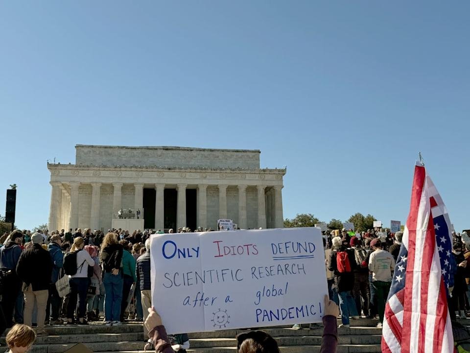 Large crowds in front of Lincoln Memorial; Person Sign Reading & quot; After global pandemic diseases, only fools fail scientific research. & quot;