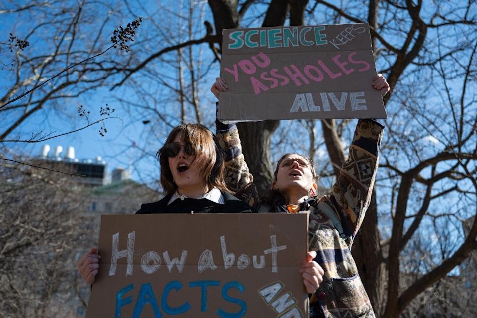 Two people have signs of protest. One reads, & quot; Science keeps you alive, & quot; And second, & quot; What about the facts? & quot;