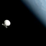 a white, conical spacecraft floats in the blackness above space. a blue and white earth can be seen along the rightmost edge of the photo