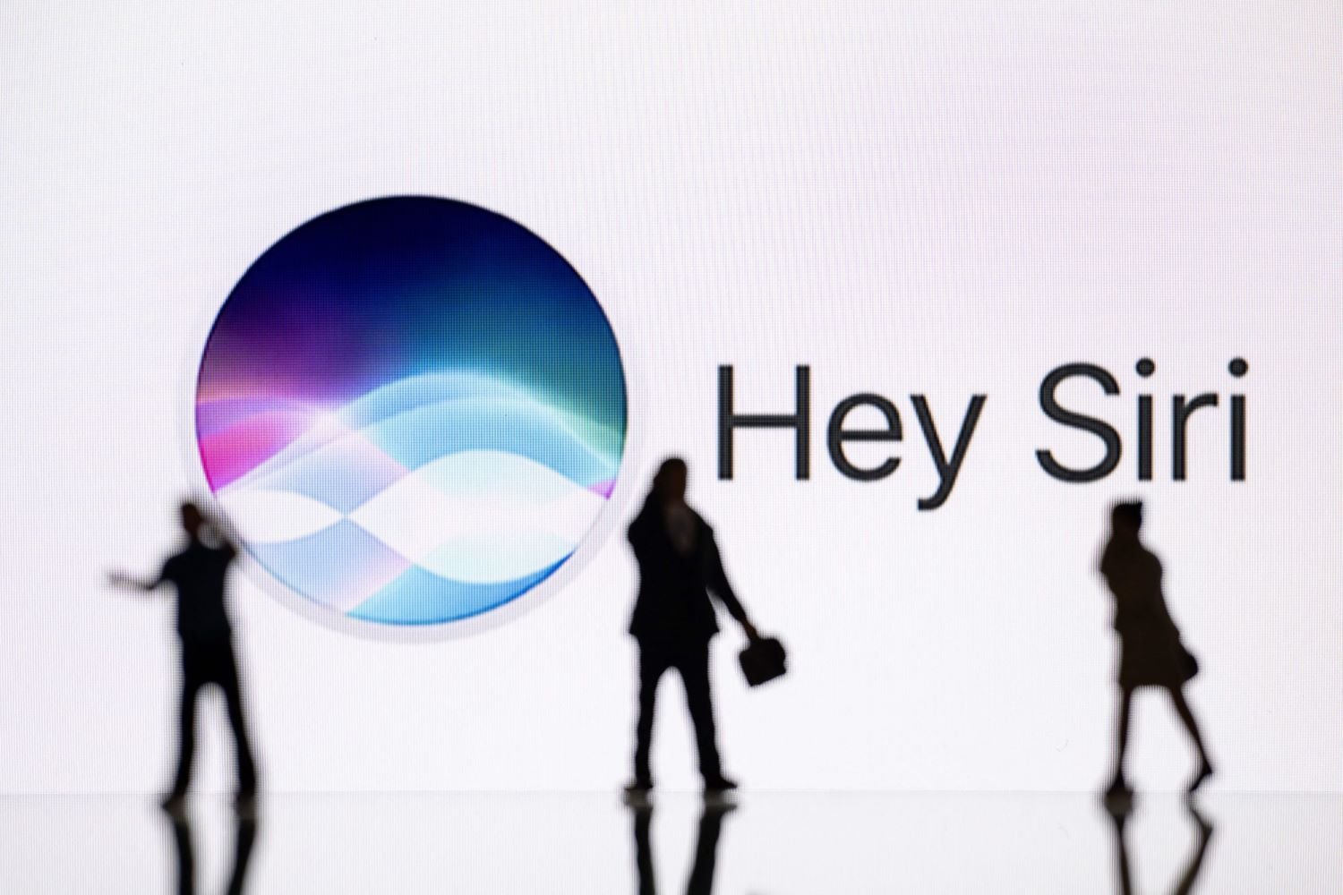 Silhouetted figures in front of a white background and the words "Hey Siri."