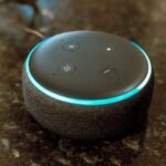 In this photo illustration, Echo Dot smart speaker with working Alexa with blue light ring seen displayed.