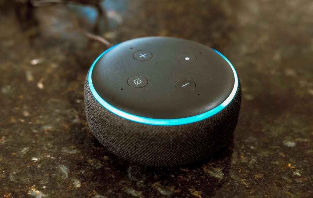 In this photo illustration, Echo Dot smart speaker with working Alexa with blue light ring seen displayed.